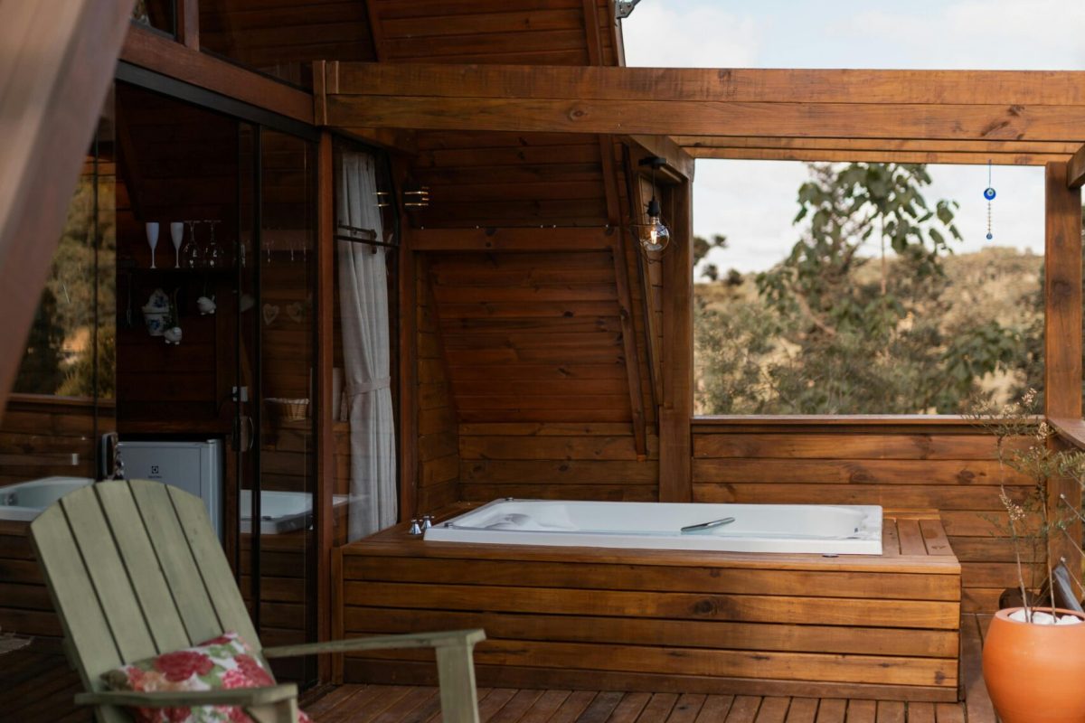 A tranquil rustic cabin featuring an outdoor deck, seating, and a hot tub, perfect for relaxation.